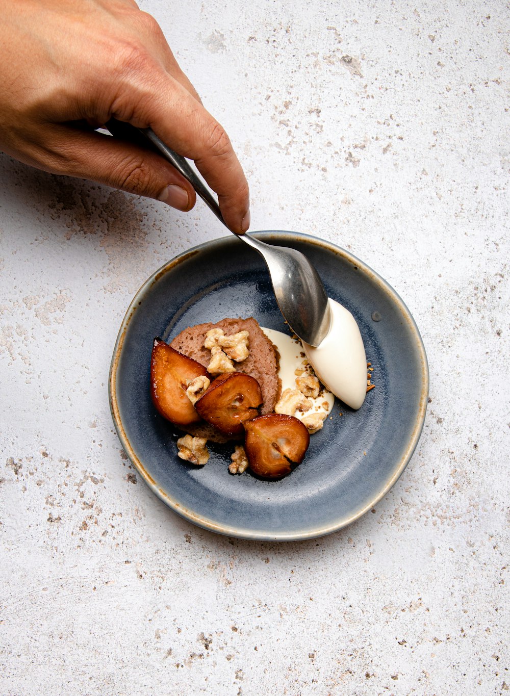 person holding stainless steel spoon on blue ceramic bowl