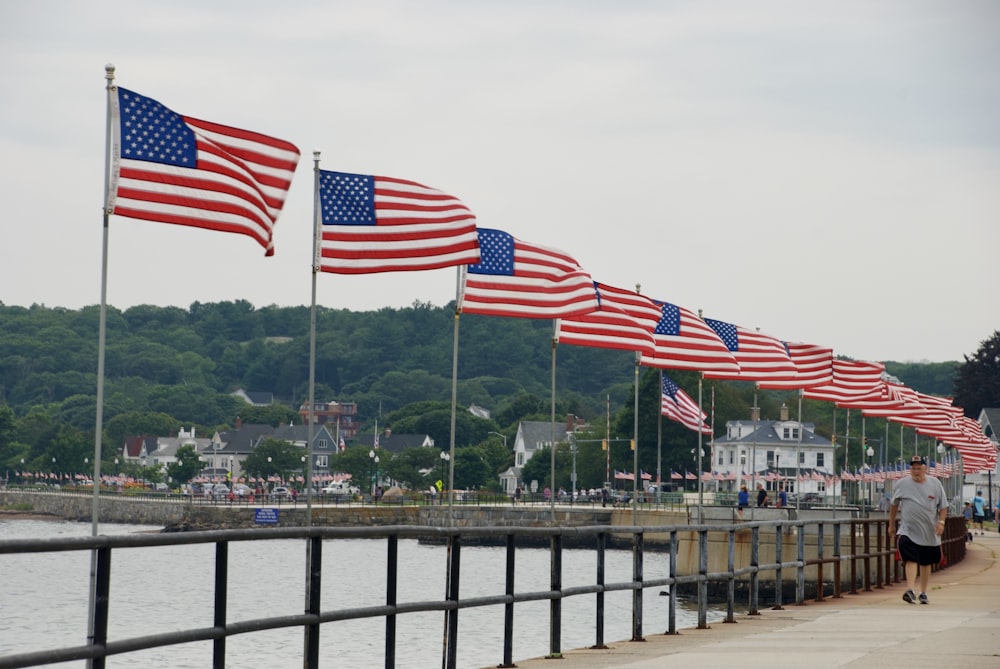 us a flag on gray metal railings near body of water during daytime