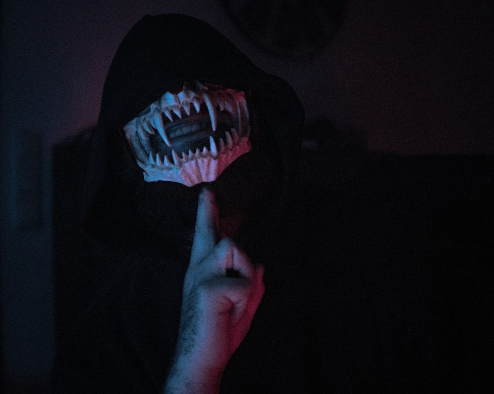 uma pessoa em um quarto escuro com uma máscara assustadora em