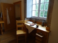 A cozy corner featuring a vintage wooden writing desk beside a large window with flowing curtains.
