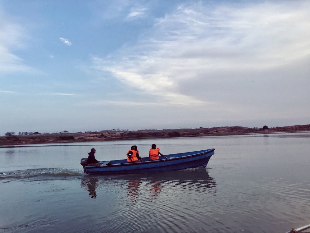 people riding on red and black boat on sea under white clouds and blue sky during