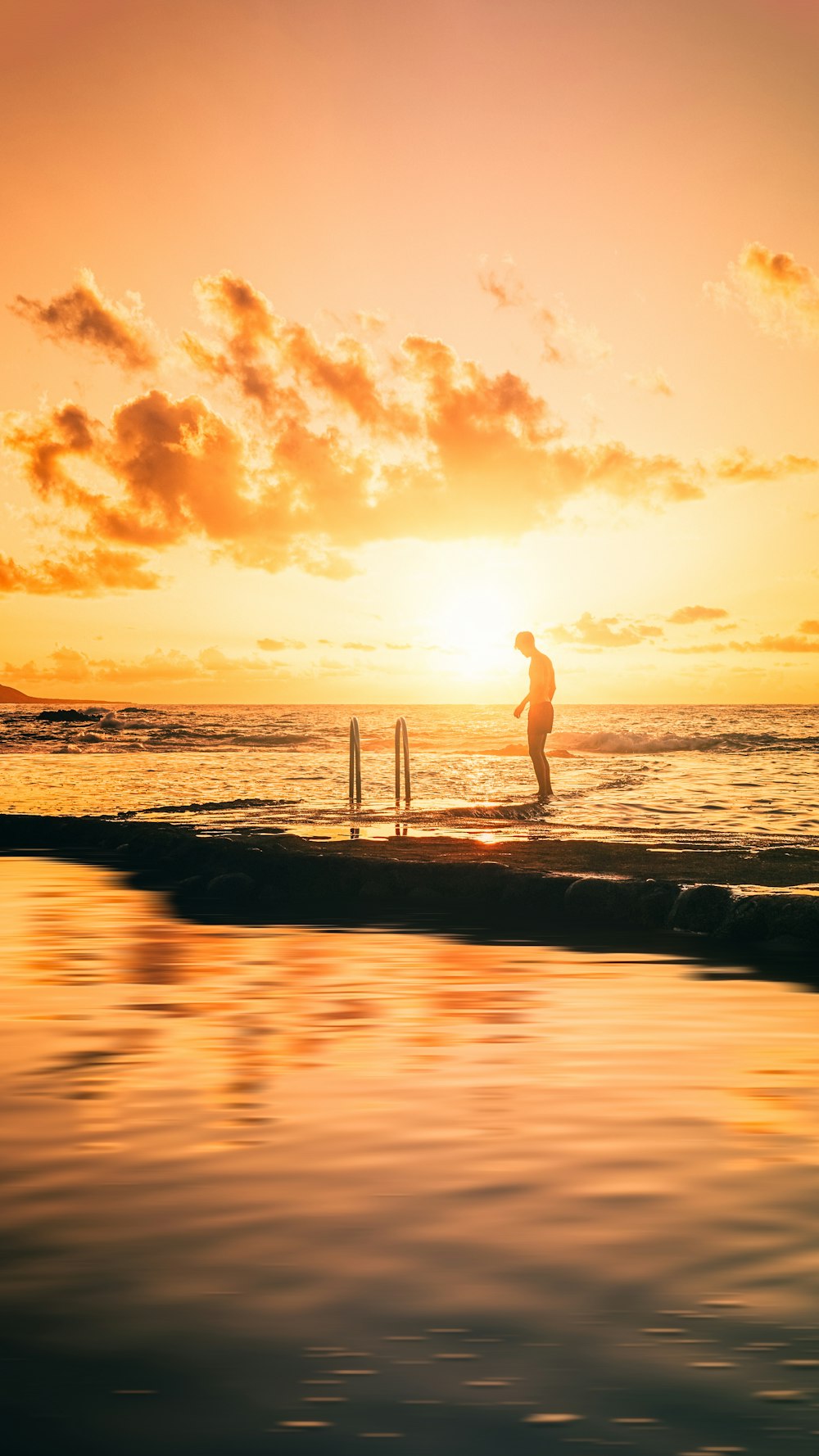 Frau in weißem Kleid steht bei Sonnenuntergang am Strand