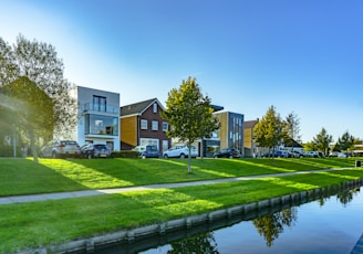 white and brown house near green grass field and body of water during daytime