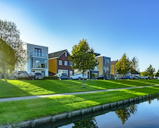 white and brown house near green grass field and body of water during daytime