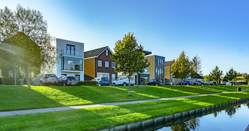 white and brown house near green grass field and body of water during daytime