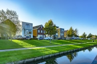 white and brown house near green grass field and body of water during daytime