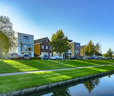 white and brown house near green grass field and body of water during daytime