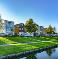 white and brown house near green grass field and body of water during daytime