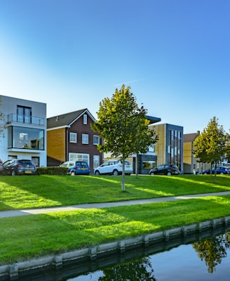 white and brown house near green grass field and body of water during daytime