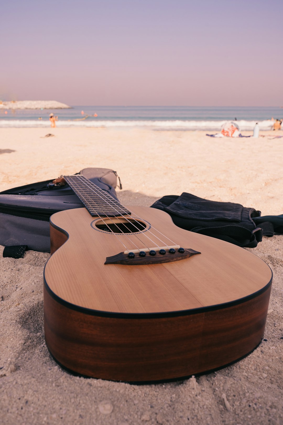 brown acoustic guitar on gray sand during daytime