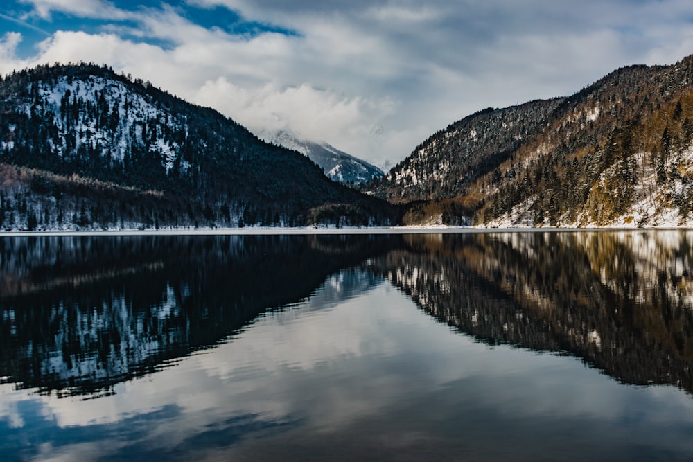 lake near mountain under cloudy sky during daytime