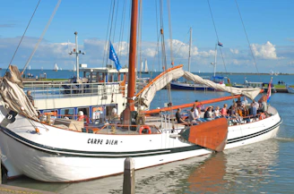 A group of sailors using a tablet app to coordinate boat rentals on a sunny dock.