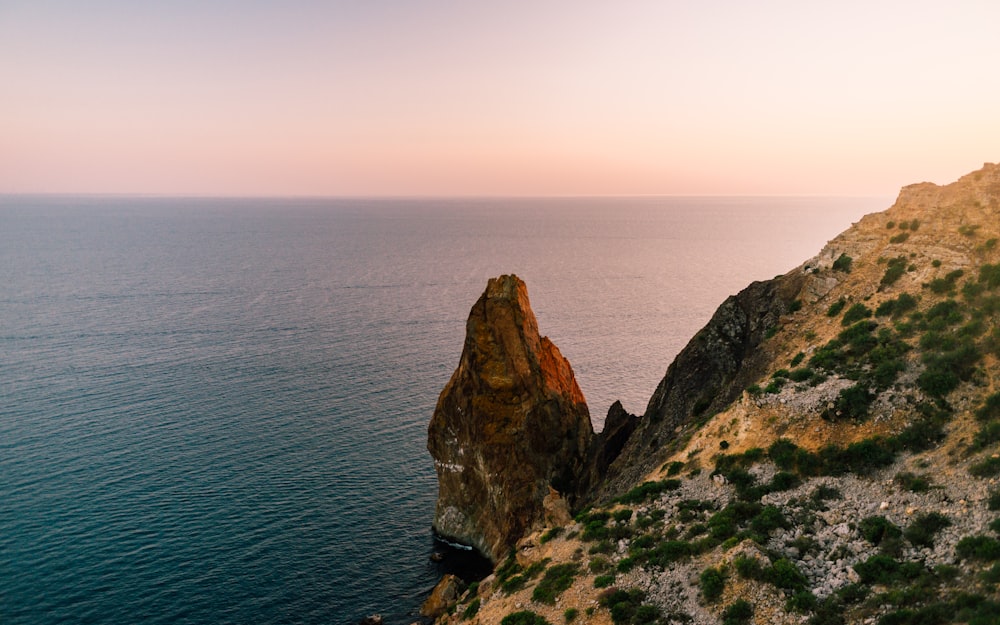 brown rock formation beside body of water during daytime