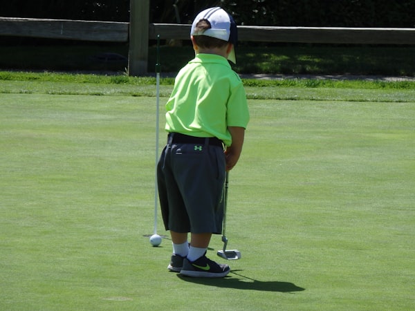 Enfant s'initiant au golf en famille sur le green