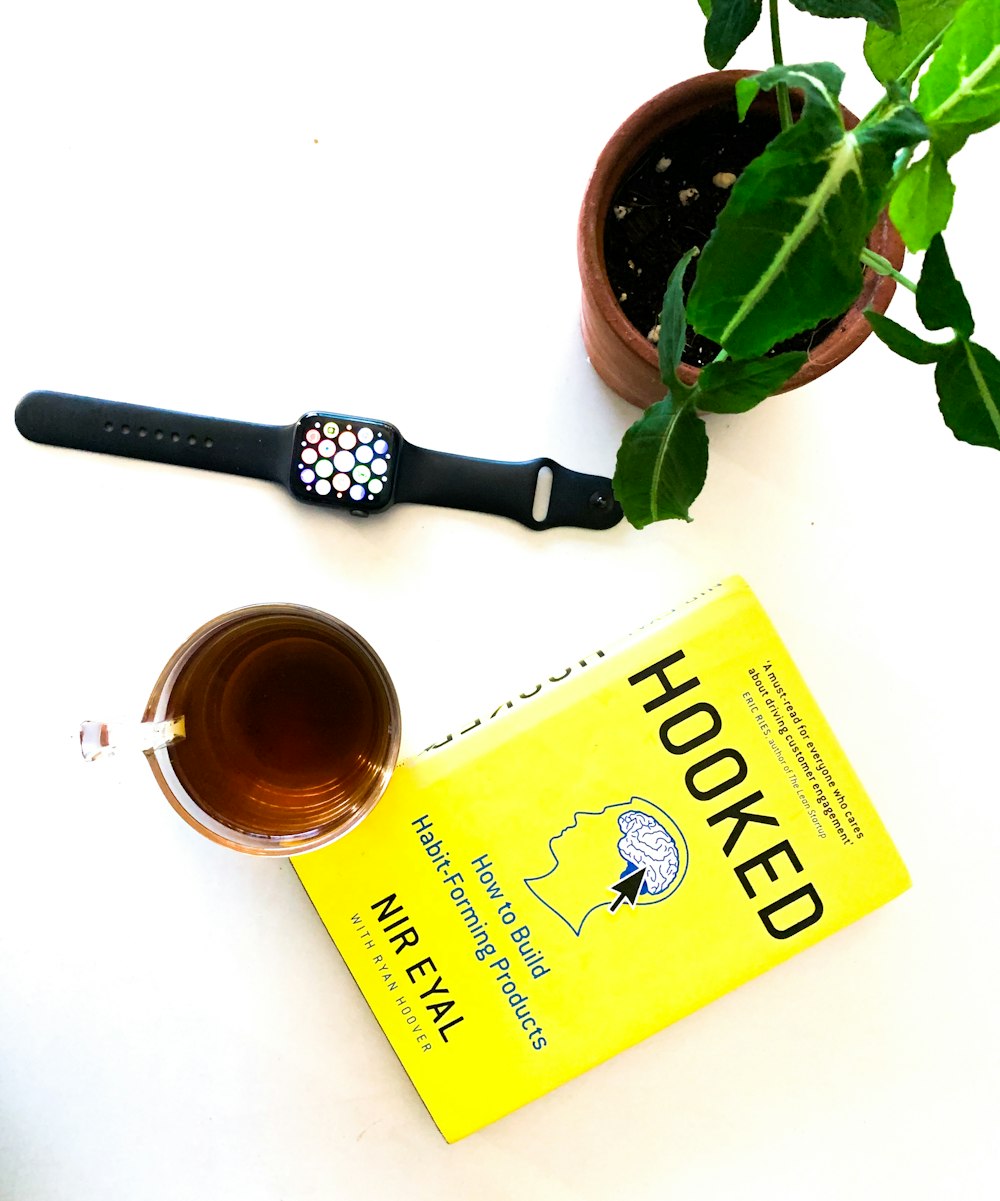 black and silver watch beside yellow and green tea box