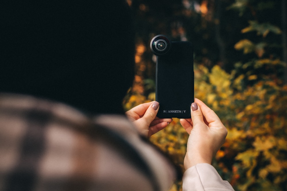 person holding black point and shoot camera