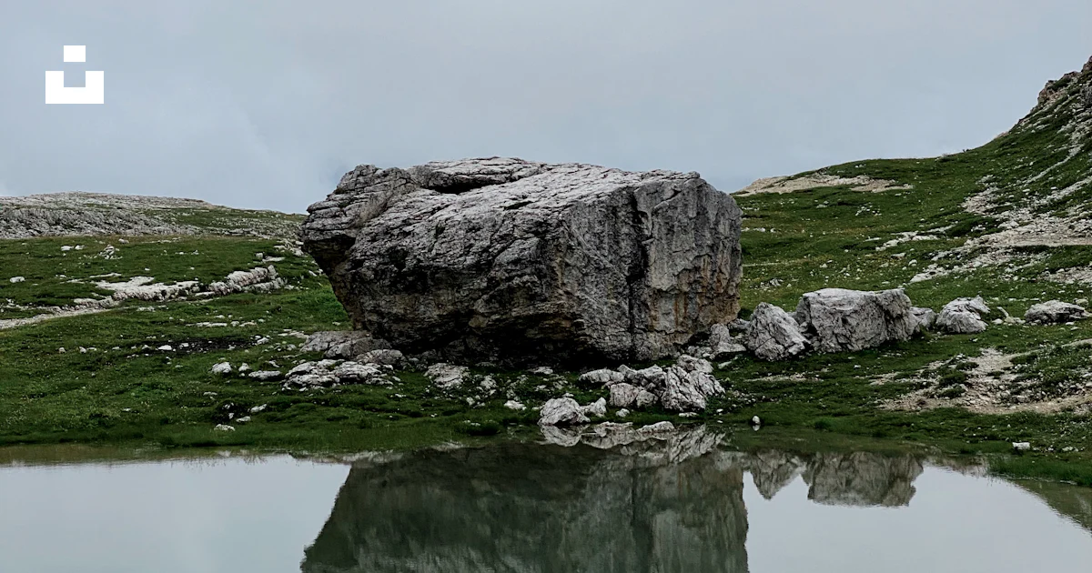 Gray rock formation on green grass field near body of water during ...