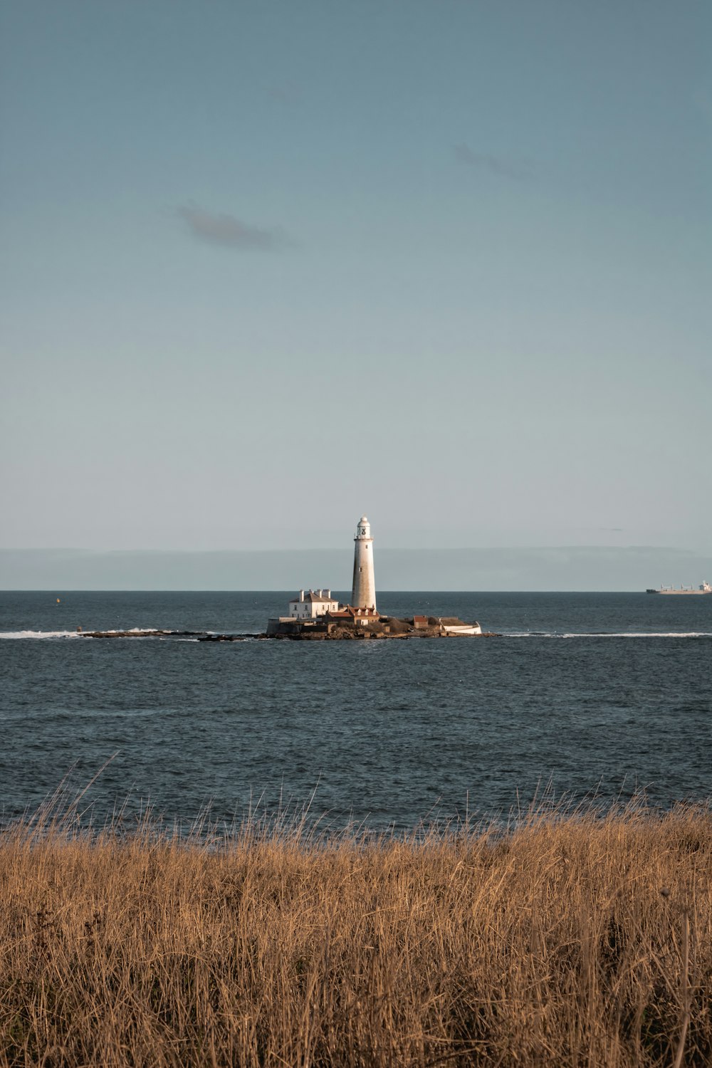 white and brown lighthouse on sea under white sky during daytime