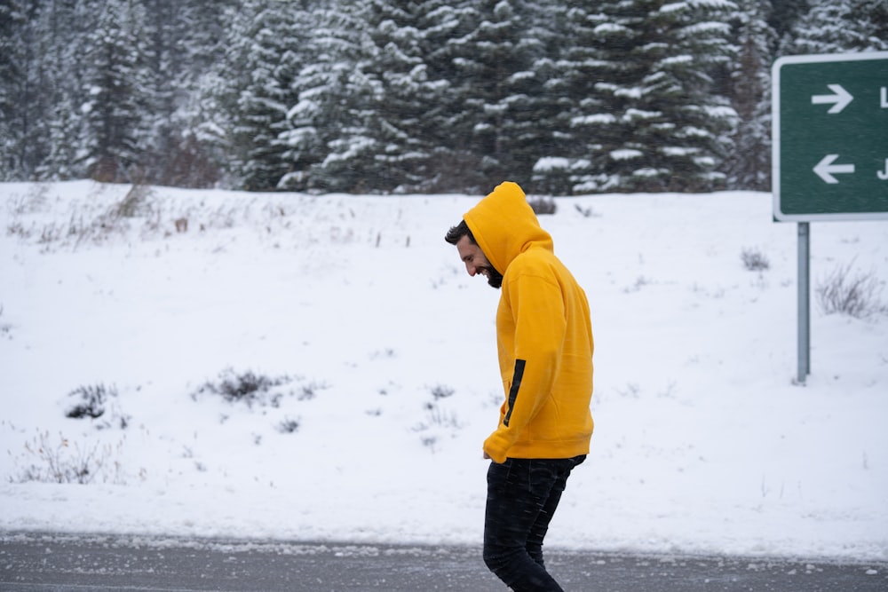 person in yellow hoodie standing on snow covered ground during daytime