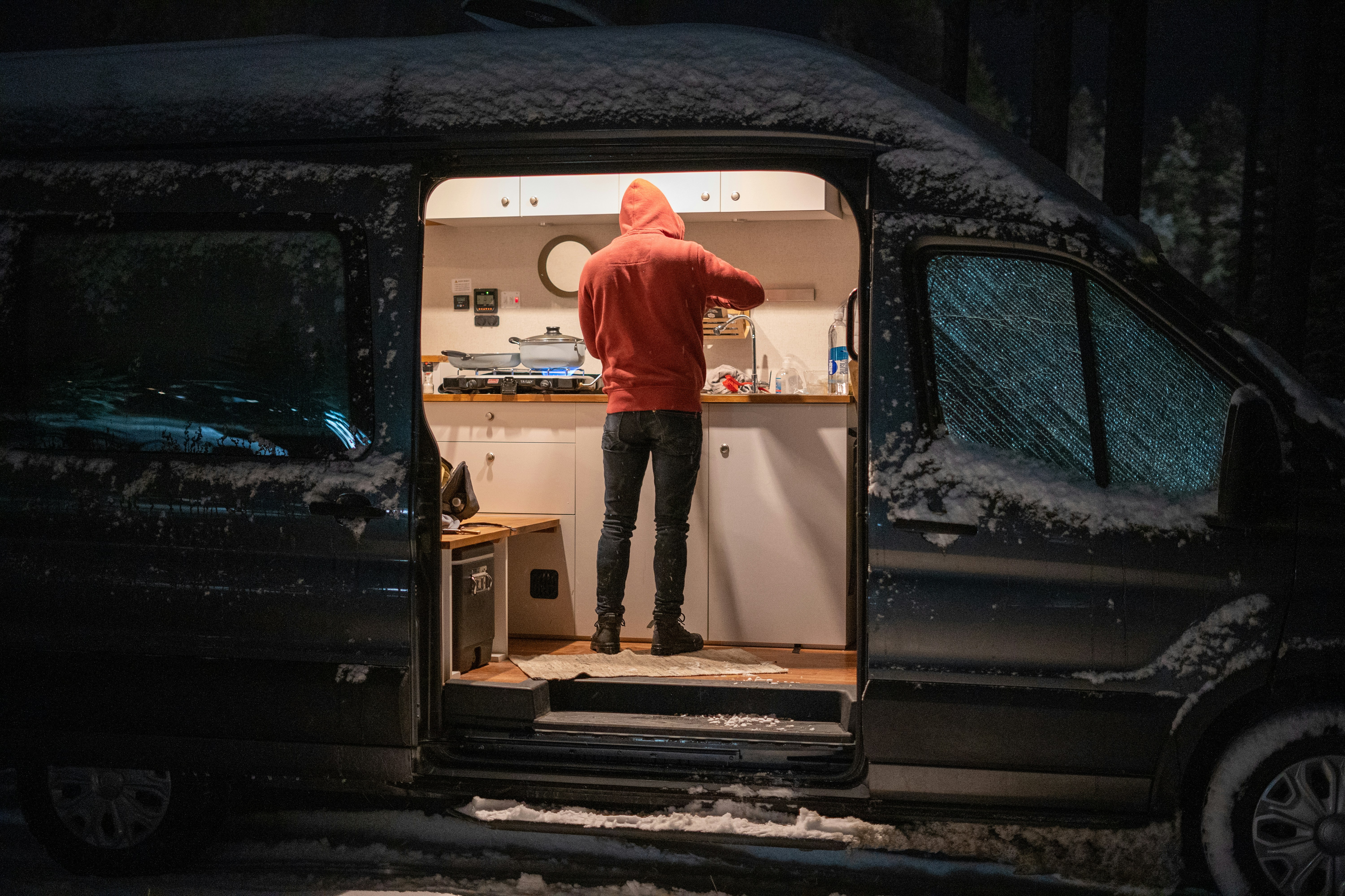 man in red hoodie standing in front of white and black car door
