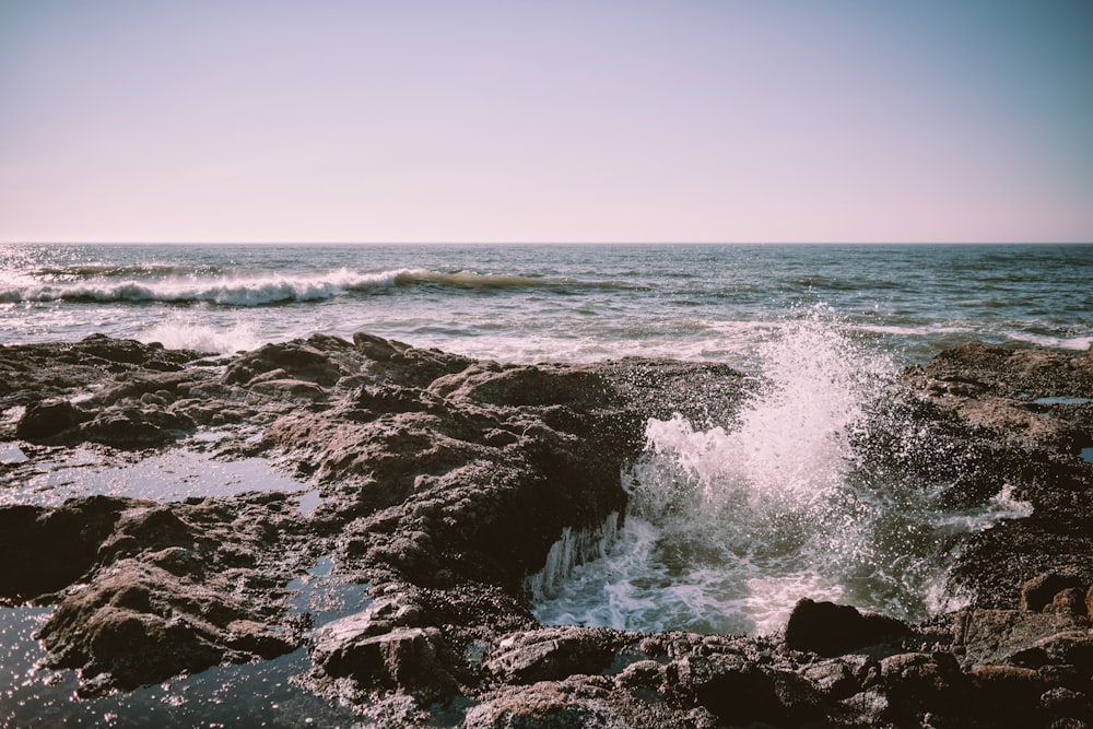 ocean waves crashing on rocky shore during daytime