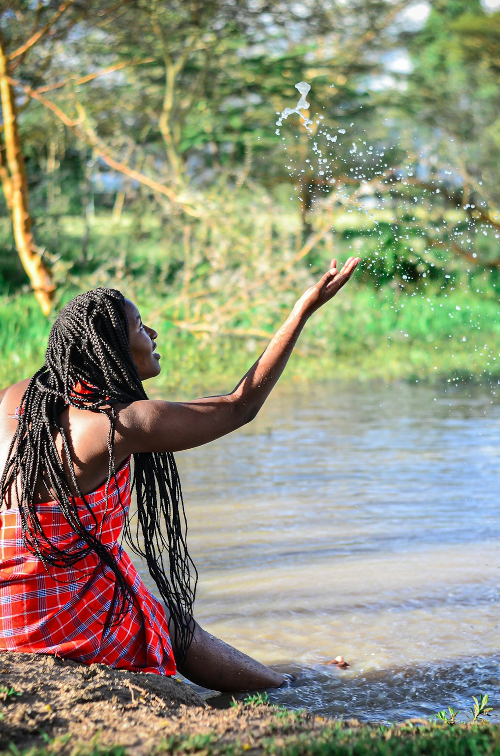 woman in red and black plaid dress standing near body of water during daytime