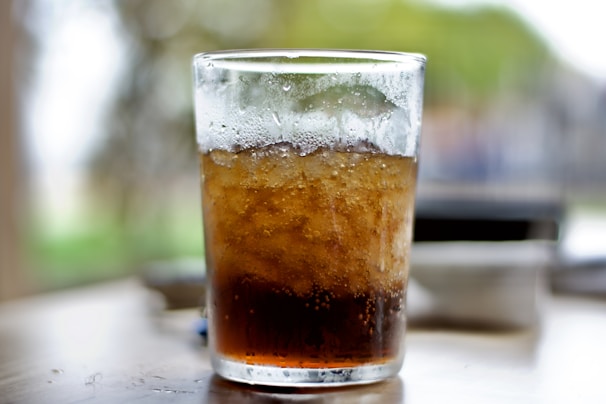 A chilled glass of sparkling soda with condensation droplets glistening in the sunlight.