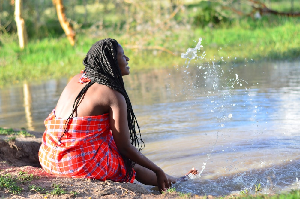 woman in red and black plaid dress sitting on brown sand during daytime