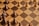 A chessboard with alternating light and dark brown squares is shown, featuring several wooden chess pieces. The pieces include pawns and other pieces forming a game setup but not arranged in a starting position. A combination of light-colored and dark-colored chess pieces are present.