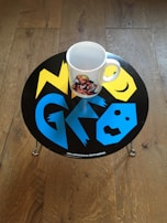 Close-up of a white mug featuring a colorful splash design in cyan, magenta, and yellow.