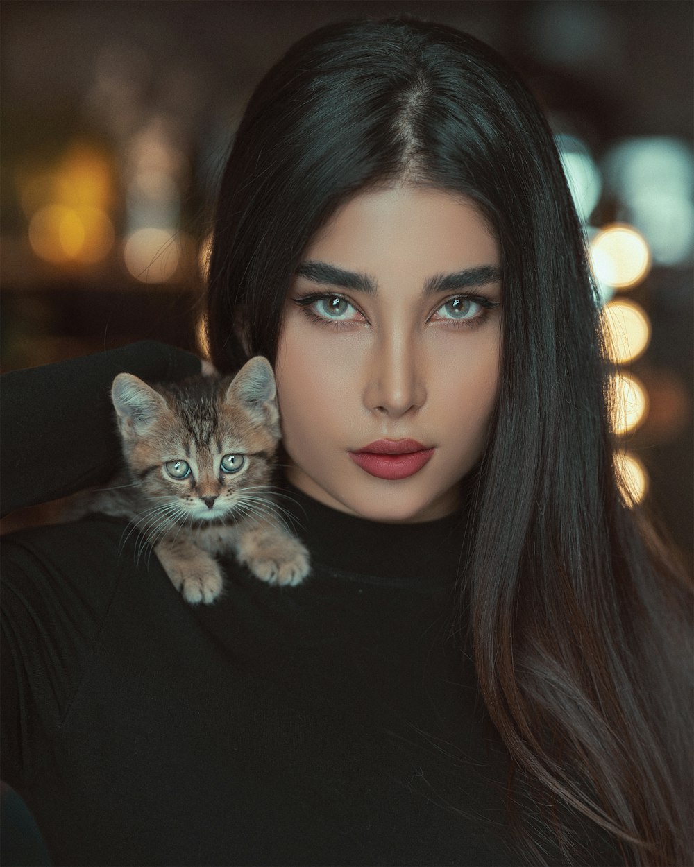 woman in black shirt with brown tabby cat on her shoulder