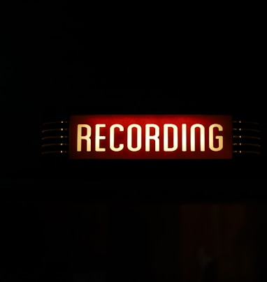 a red recording sign lit up in the dark
