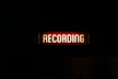 a red recording sign lit up in the dark