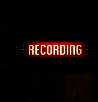 a red recording sign lit up in the dark