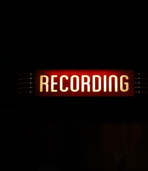 a red recording sign lit up in the dark