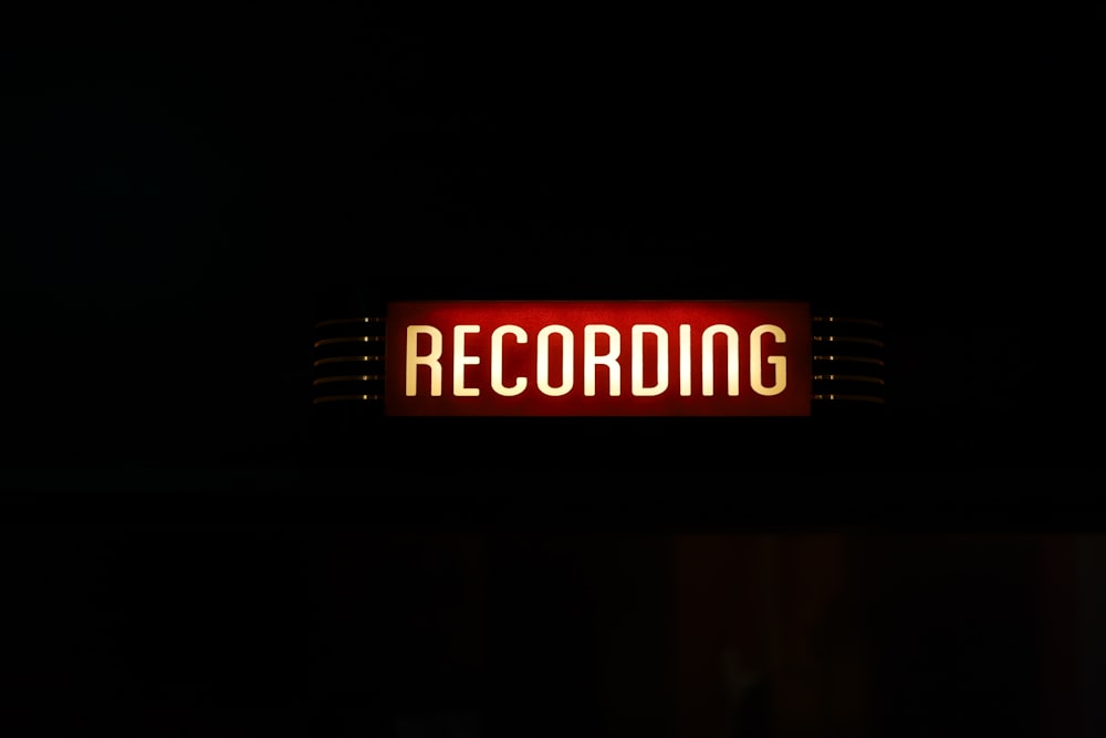 a red recording sign lit up in the dark