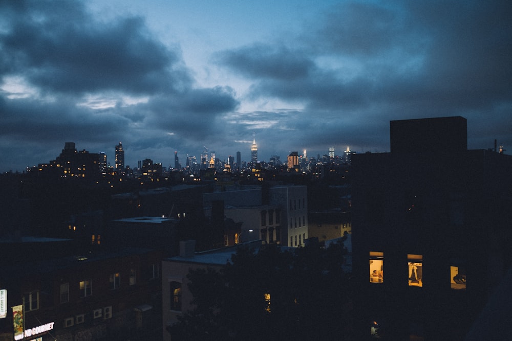 city buildings under gray clouds during night time