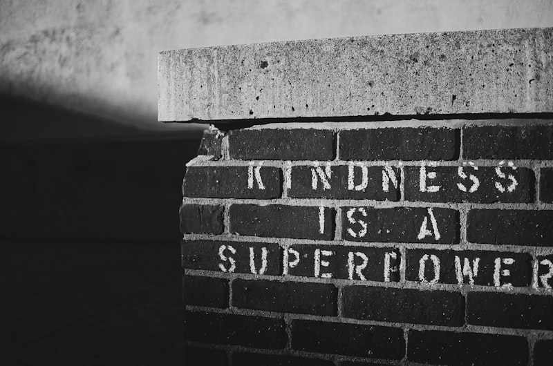 Brick wall with the phrase “kindness is a superpower” painted on it.