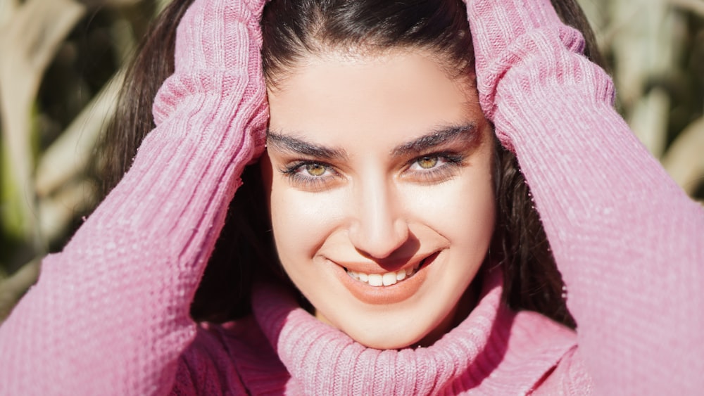 femme en pull en tricot rose souriant