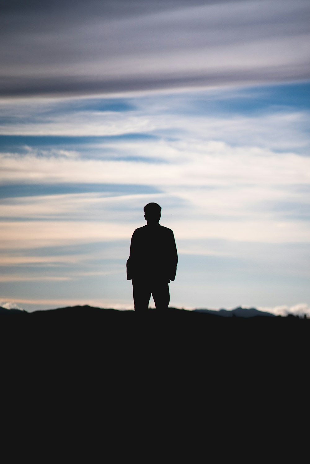 silhouette of man standing on top of mountain during sunset