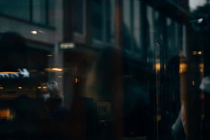 A moody shot of the butcher’s shop window at night, shadows of passersby distorted on the glass.