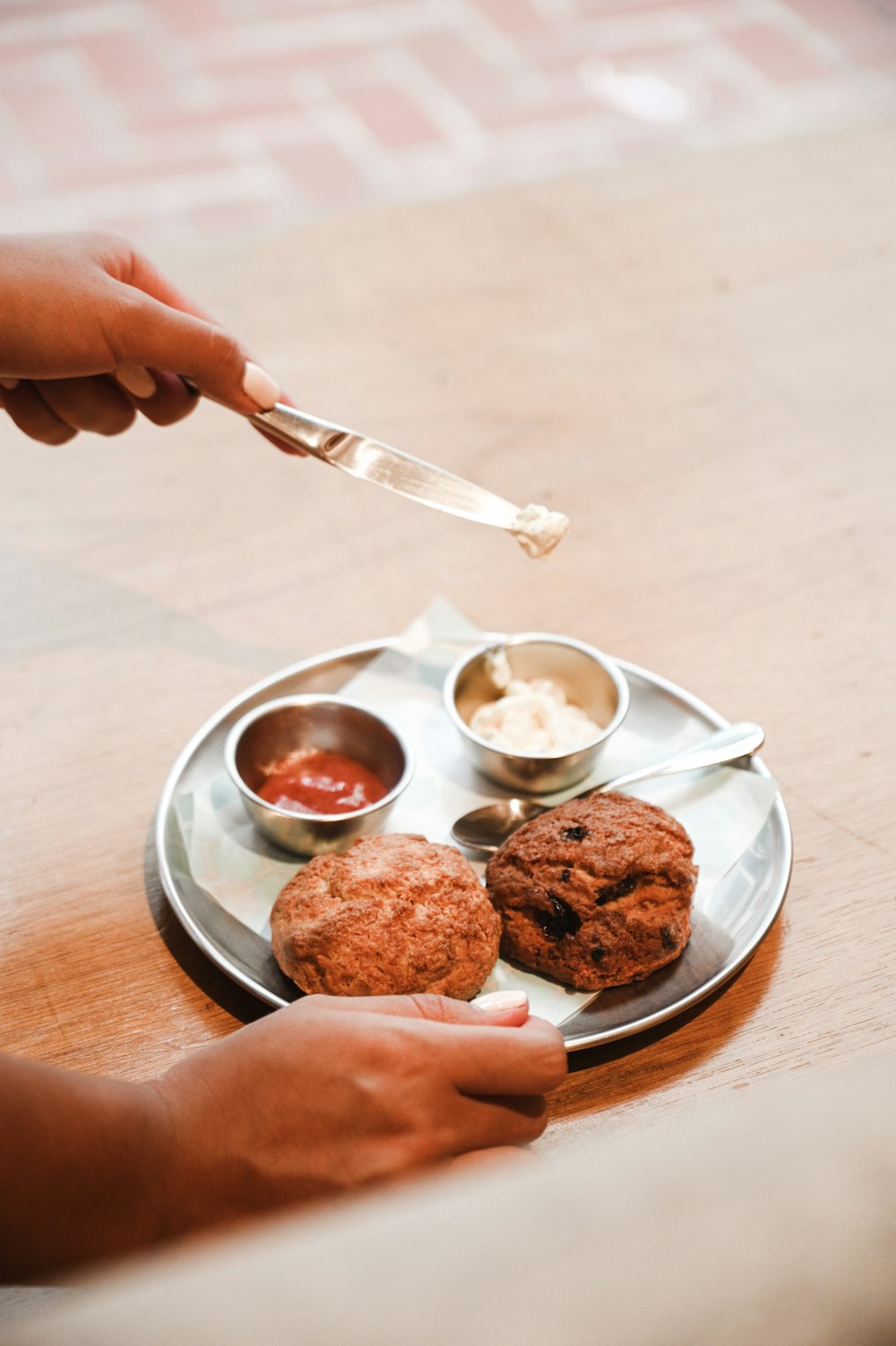 person holding stainless steel bread knife and white ceramic bowl with food