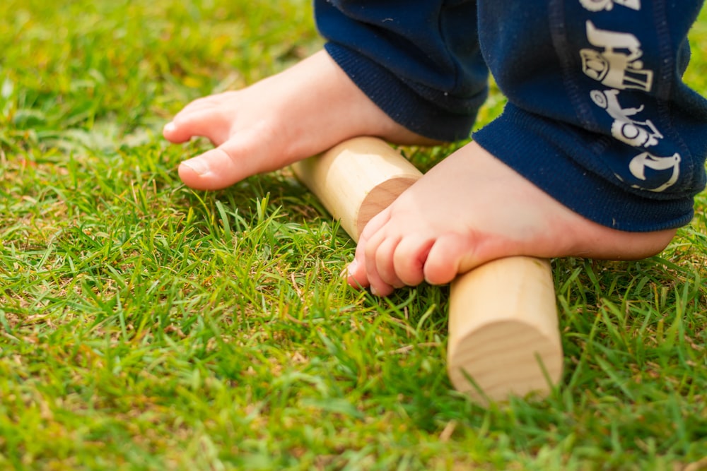 child in blue long sleeve shirt and brown pants sitting on green grass field