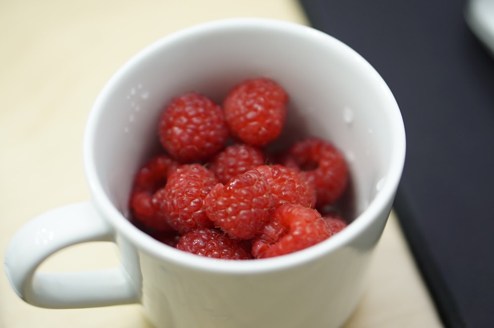 Fresas rojas sobre taza de cerámica blanca