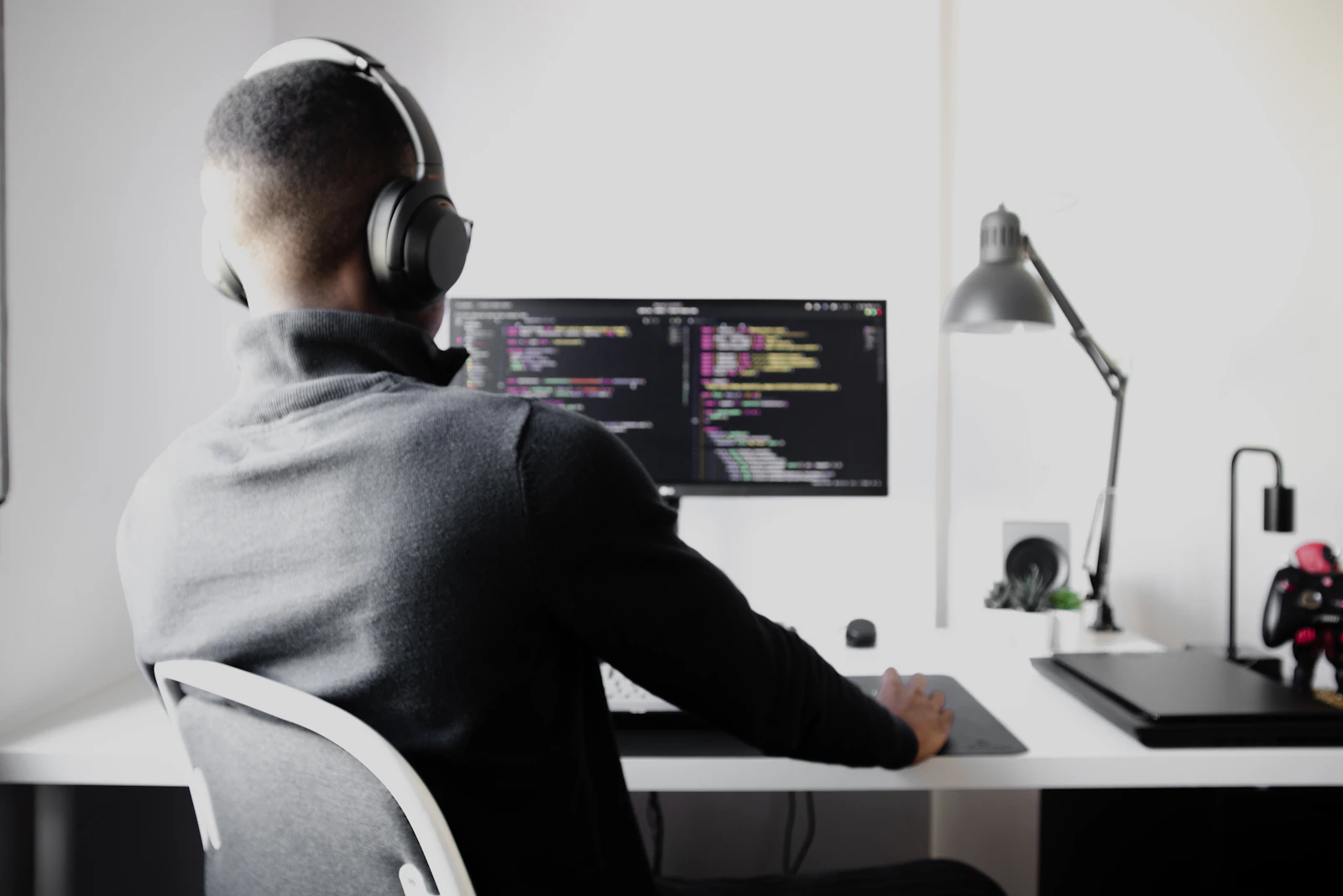 Developer with headphones working at a monitor, from behind