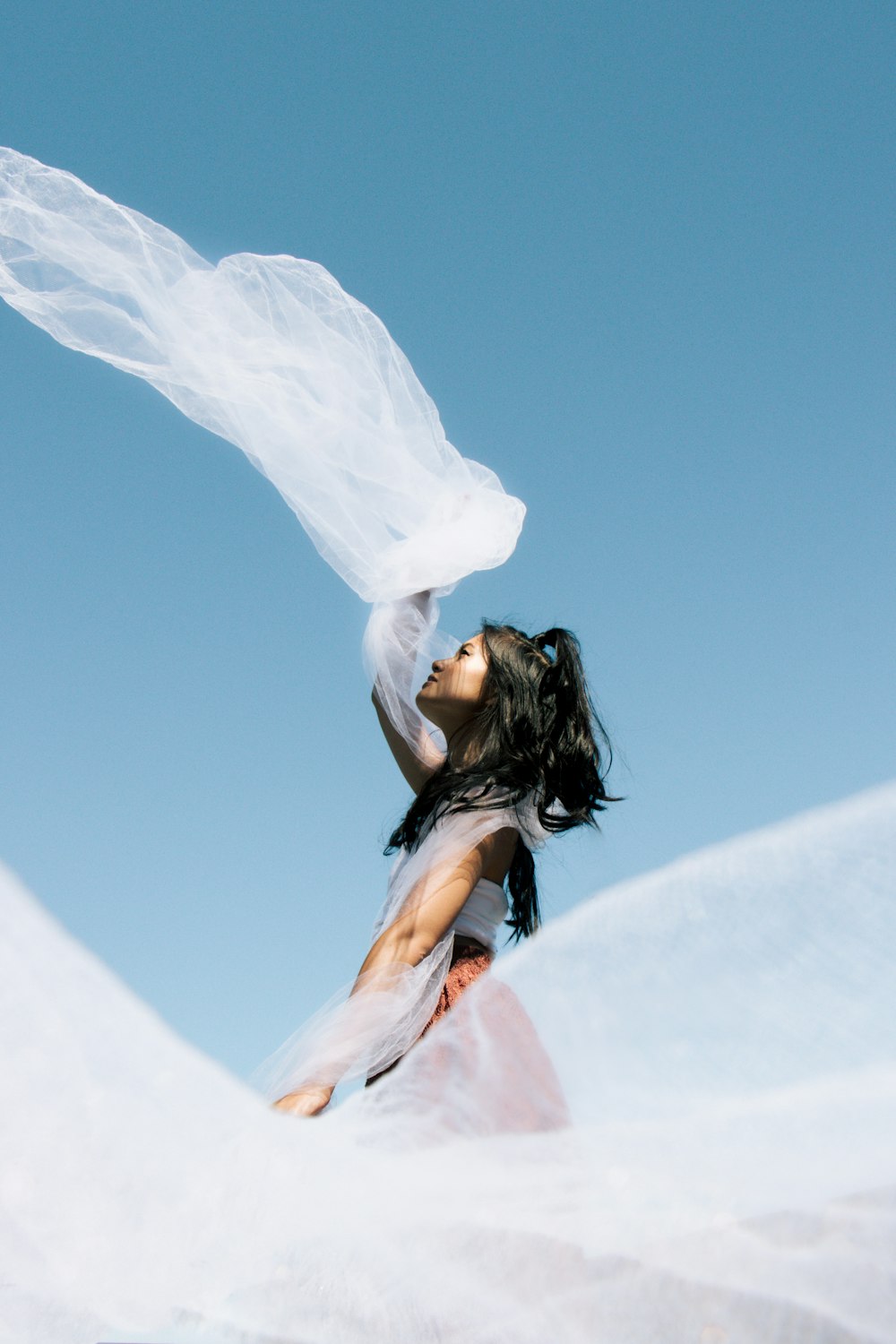 mulher no vestido cor-de-rosa que segura o têxtil branco