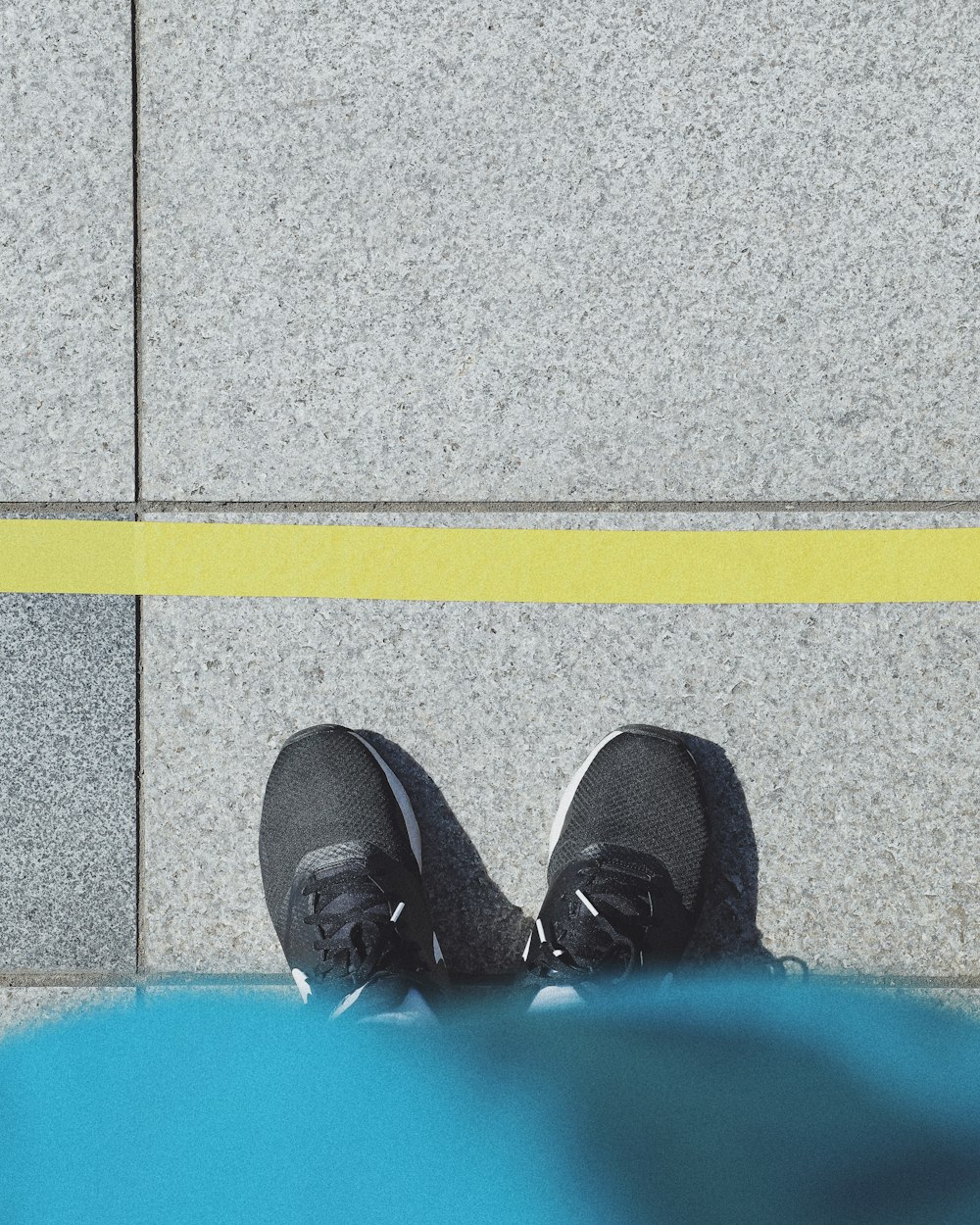 灰色のコンクリートの床に立つ黒い靴を履いた人
