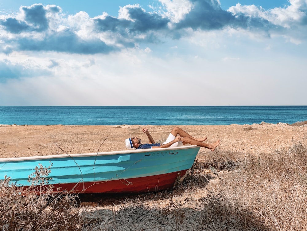 red and blue boat on seashore during daytime