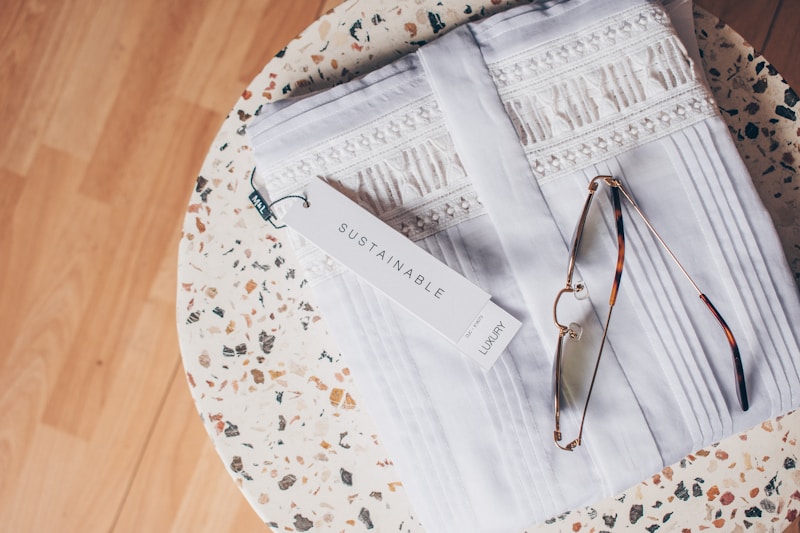 Sustainable fashion: sunglasses sitting on folded white shirt on top of terrazzo side table