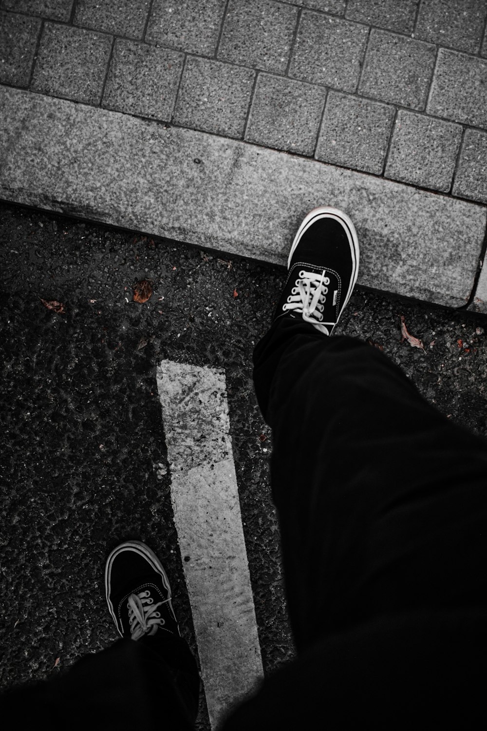 person in black pants wearing black and white sneakers